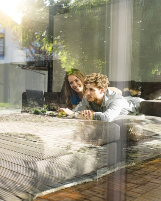 Ein junges Paar ist in ihrem Eigenheim gemeinsam am Laptop.